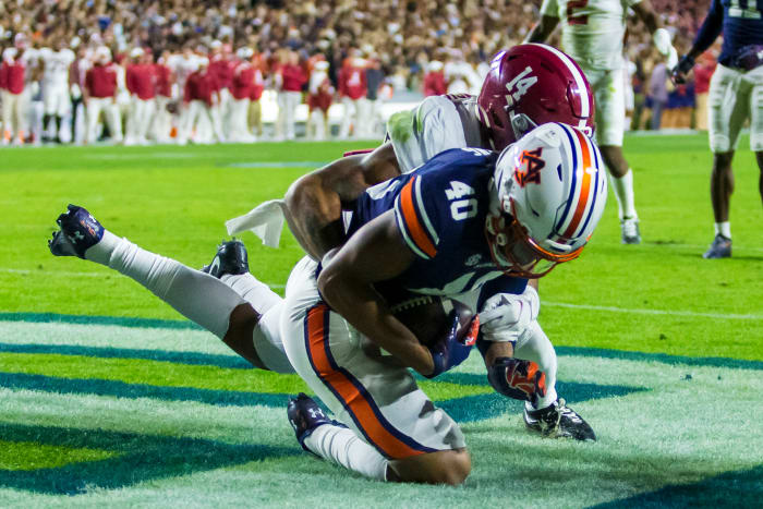 Auburn tight end Landen King (40) makes a one-handed grab to score a touchdown despite Alabama defensive back Brian Branch (14) holding his left arm during the first overtime of an NCAA college football game, Saturday, Nov. 27, 2021, in Auburn, Ala. The touchdown sent the game to a second overtime, a game won in four overtimes by Alabama, 24-22.
